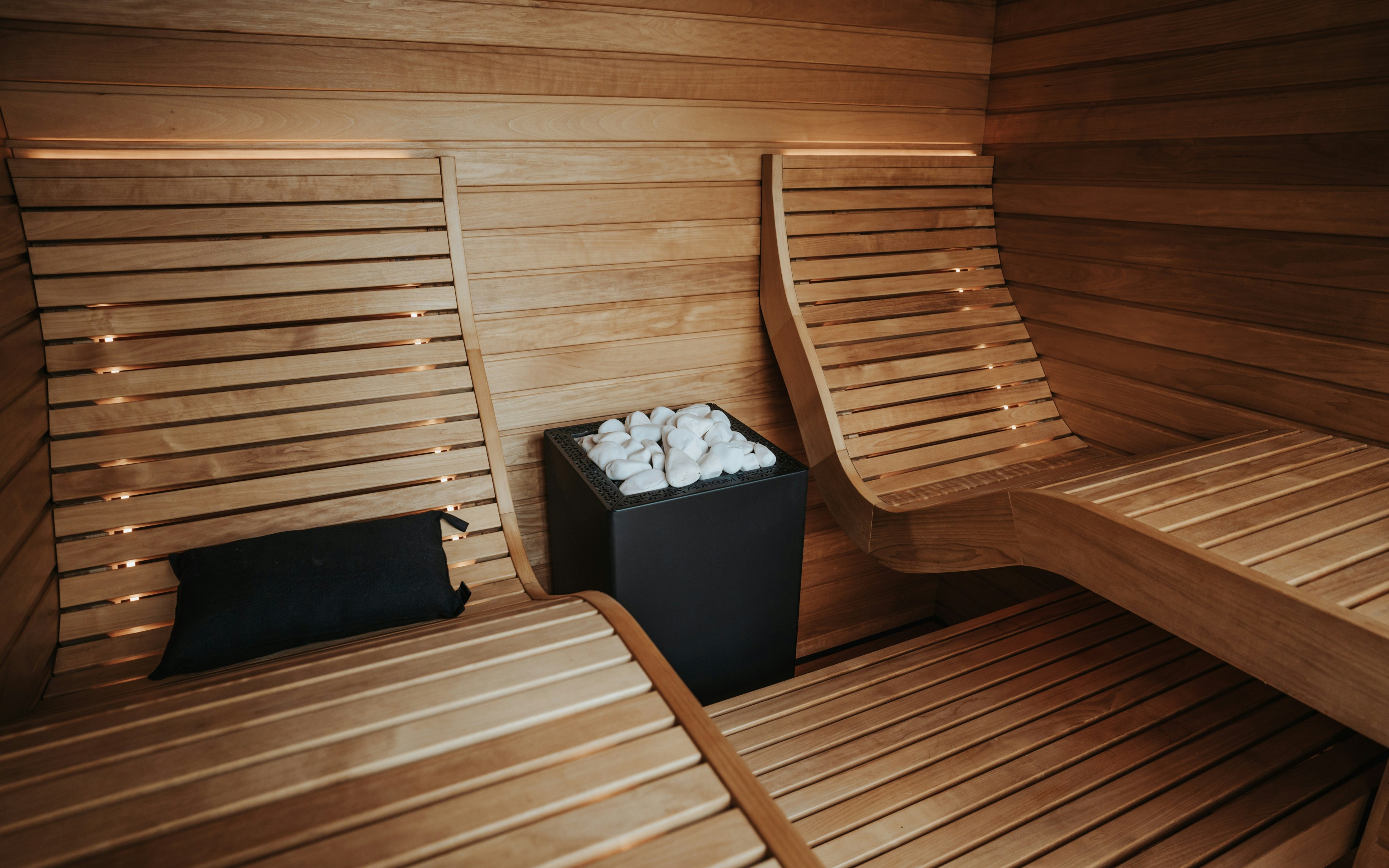 Moderne houten sauna met banken en kachel, ontworpen voor ontspanning en huidverjonging.