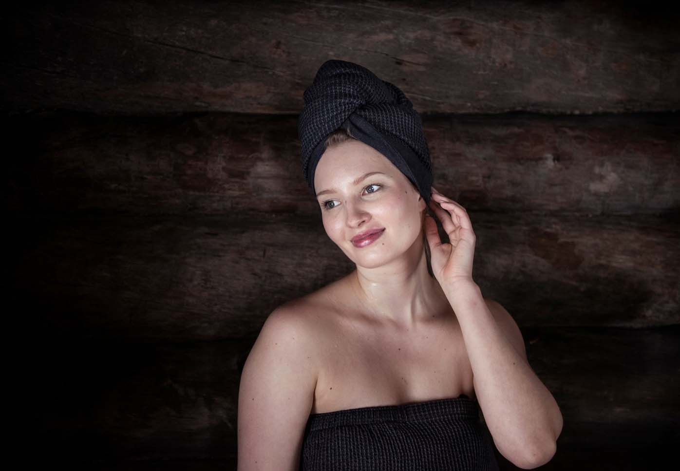 Vrouw in een sauna met een handdoek om haar haar.