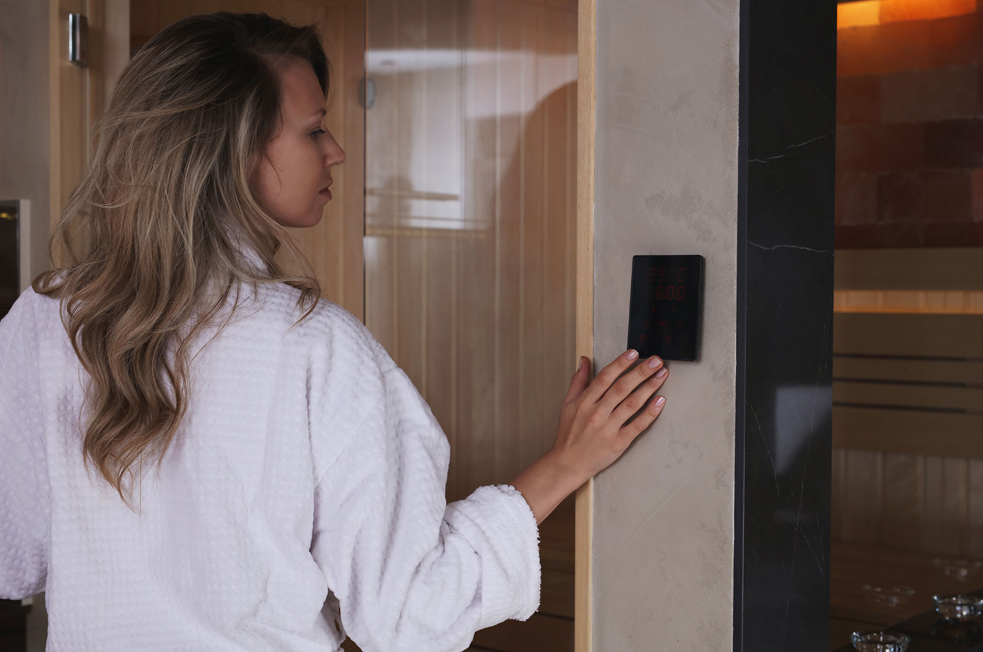 Een vrouw stelt het bedieningspaneel van de sauna af.
