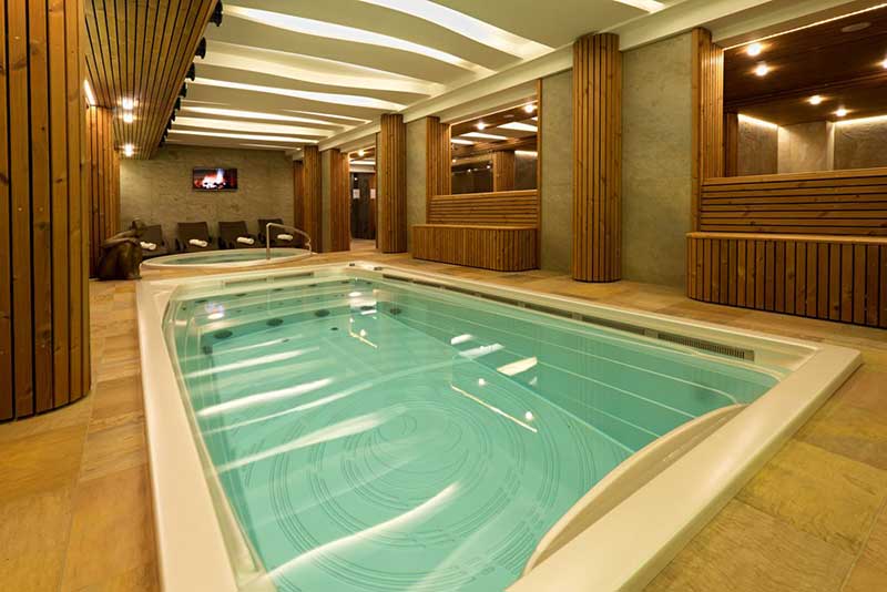 Een overdekte USSPA-zwemspa is geïnstalleerd in een wellnessruimte met een aparte ontspanningszone.