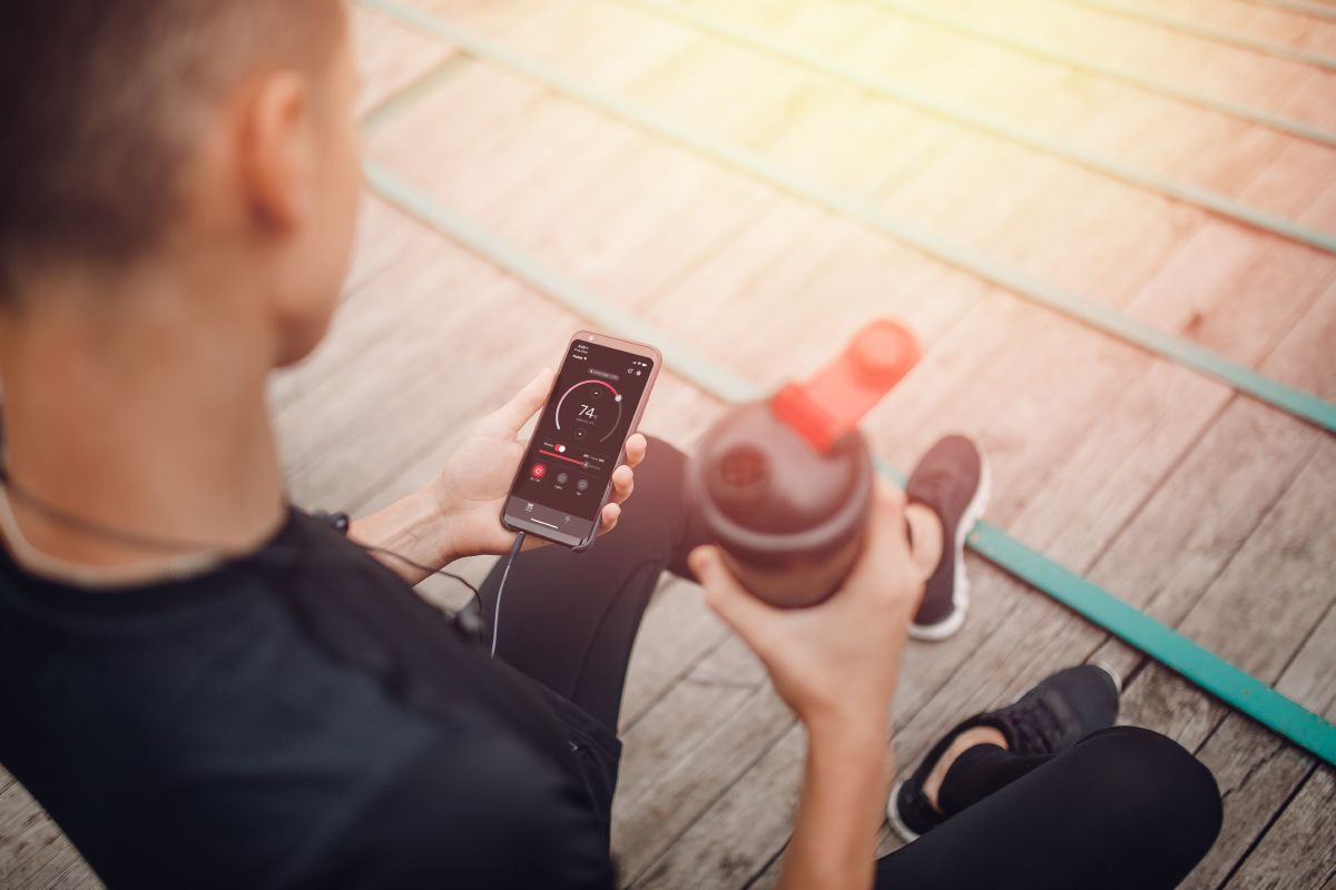 atleet met een waterfles en telefoon in zijn handen