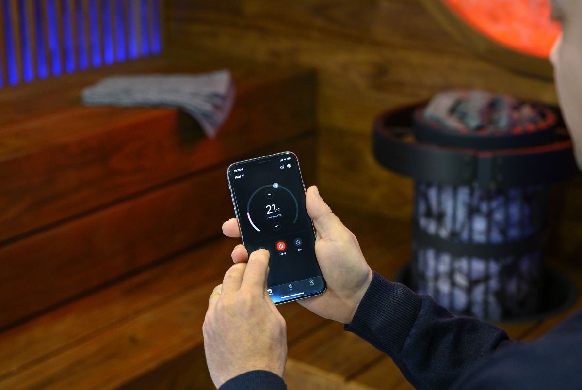 persoon die saunaapparatuur bedient met de MyHarvia mobiele app