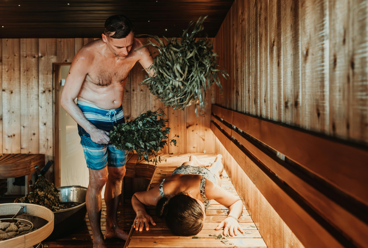 Een man slaat een vrouw met een berkenroede in de sauna – een traditioneel saunaritueel voor ontspanning.